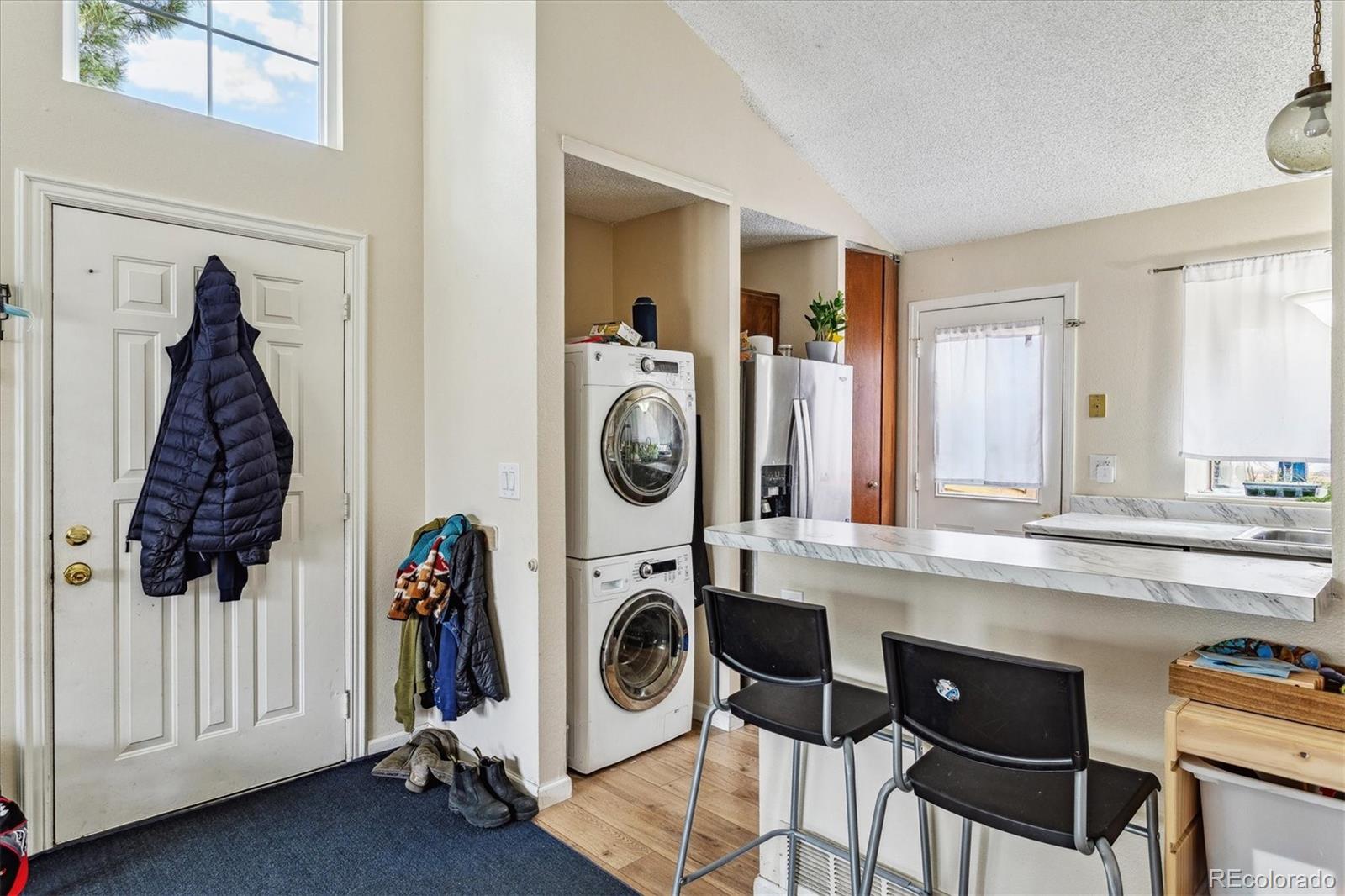 Kitchen and entry with a breakfast bar, stacked washer and dryer, and front door.