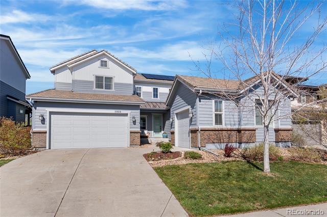 Two-story gray house with a brick facade, attached garage, and wide concrete driveway.
