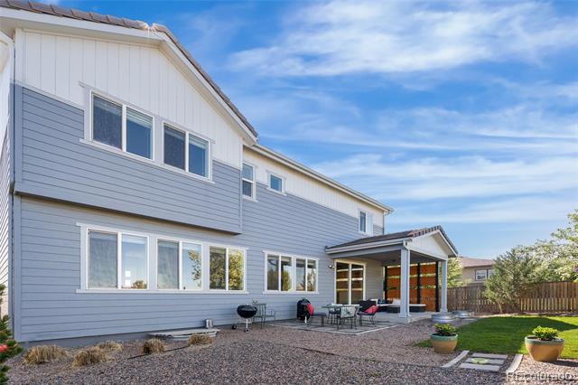Two-story gray-sided home with a covered patio, outdoor dining set, and fenced backyard.