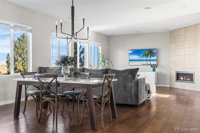 Open-plan living and dining room with a gray sectional, wood dining table, and built-in fireplace.