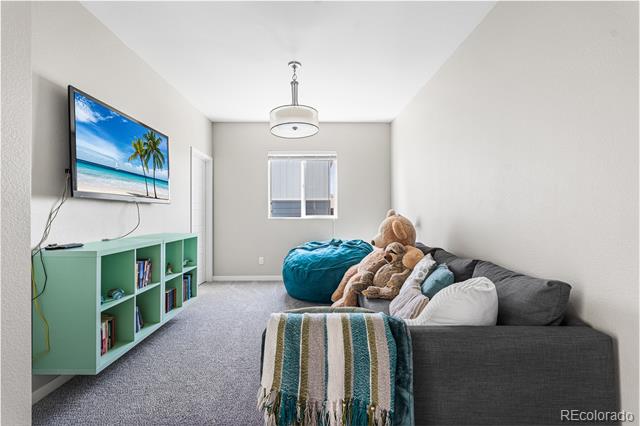 Family room with a gray sectional, plush toys, teal beanbag, and wall-mounted television.