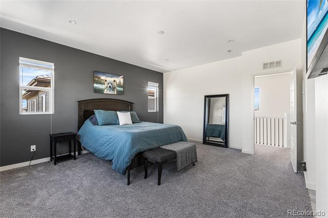 Bedroom with blue bedding, a dark accent wall, and gray carpet.