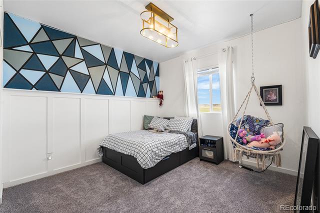 Bedroom with a geometric blue-and-black accent wall, platform bed, and hanging chair.