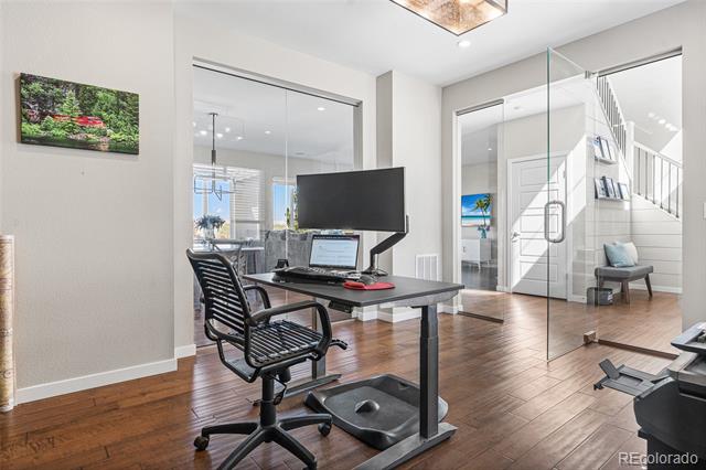 Home office with a standing desk and glass partition beside the staircase.