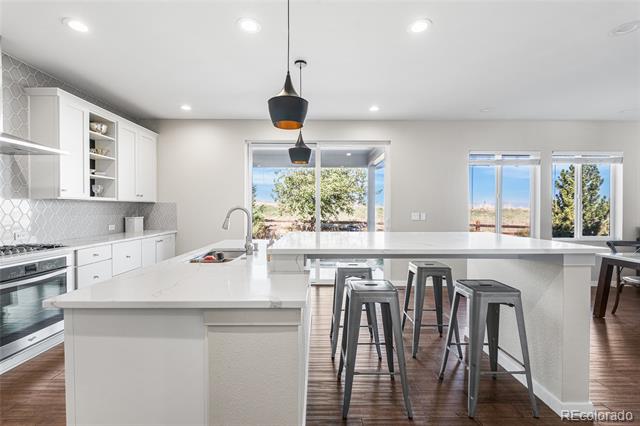 Modern white kitchen with a large island, bar stools, and sliding glass doors.