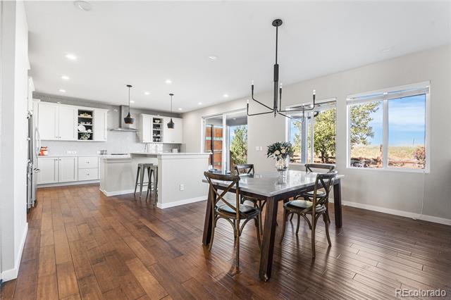 Open kitchen and dining area with white cabinets, a large island, and a dark wood dining table.