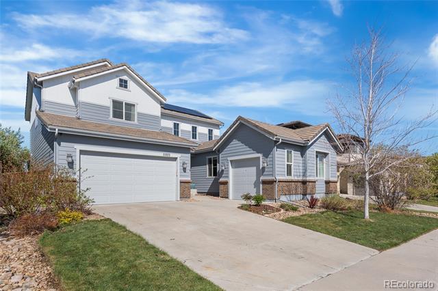 Two-story gray house with attached garages, a wide driveway, and landscaped front yard.