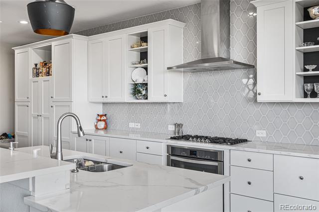 Modern kitchen with a marble island, white cabinets, and gray geometric tile backsplash.