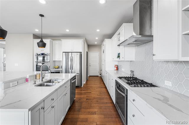 Modern white kitchen with a large island, stainless-steel appliances, and warm wood floors.