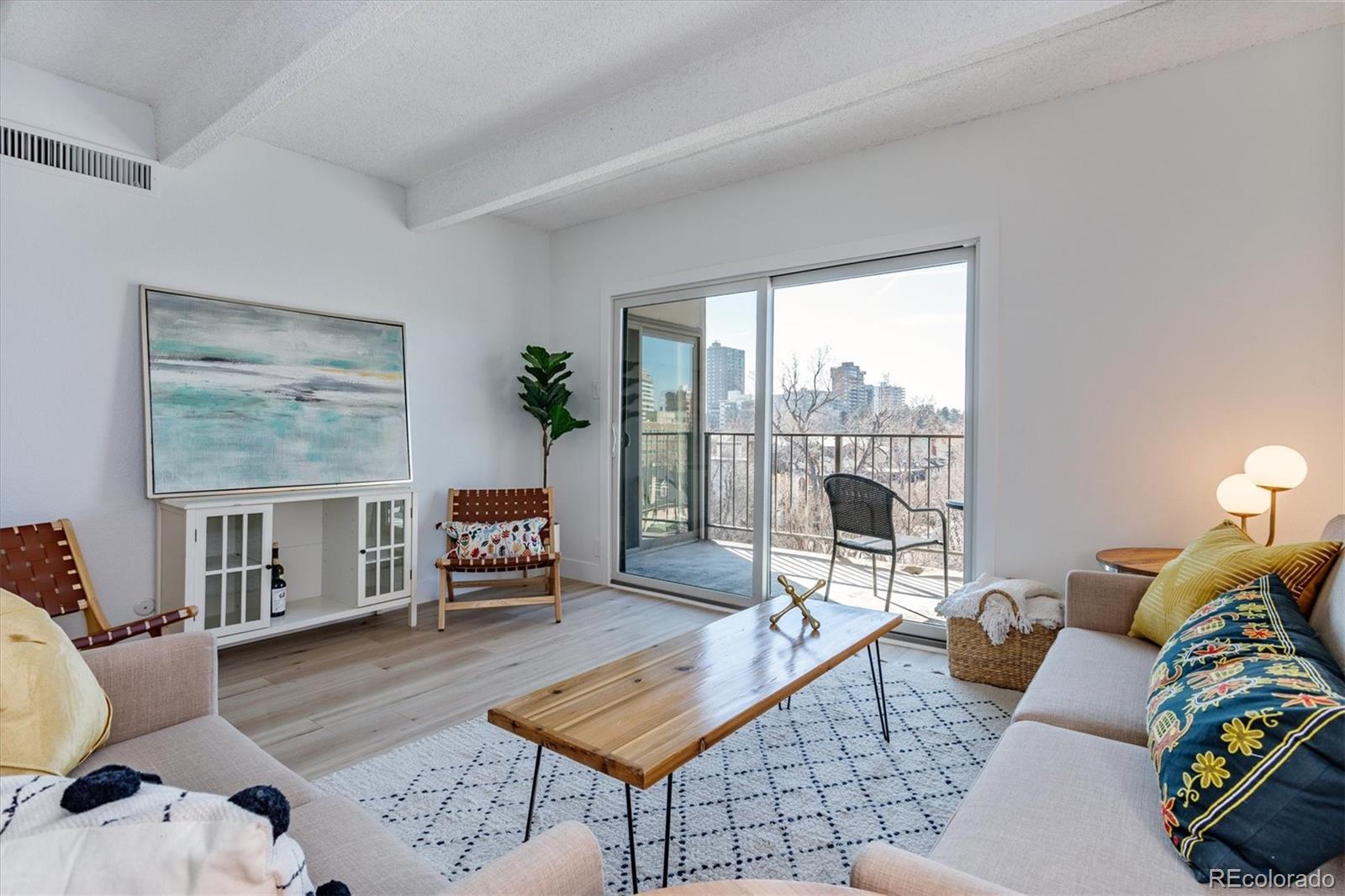 Furnished living room with a balcony, city views, and a patterned rug.