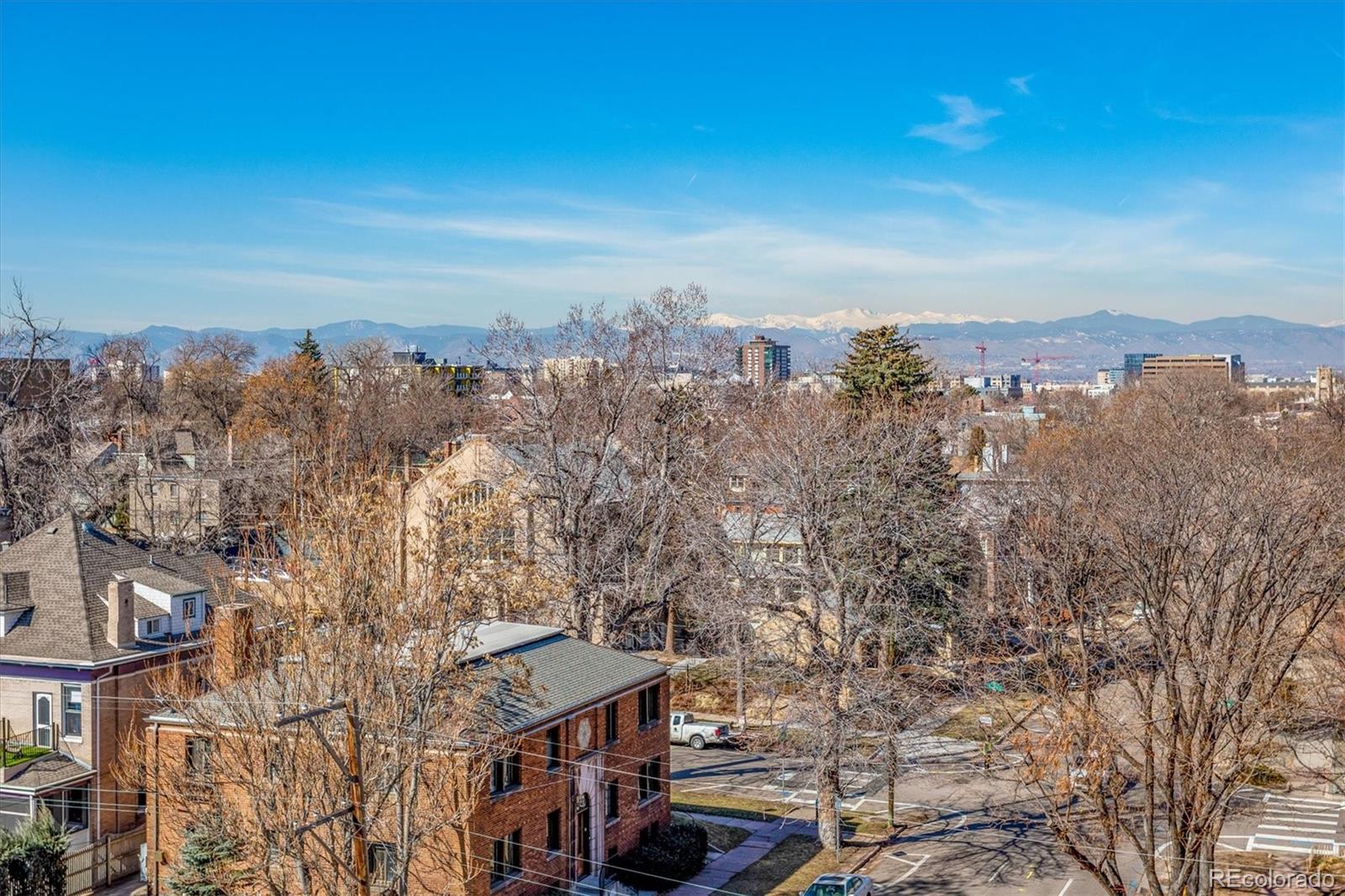 Denver rooftops and skyline with the snow-capped Rocky Mountains in the distance.