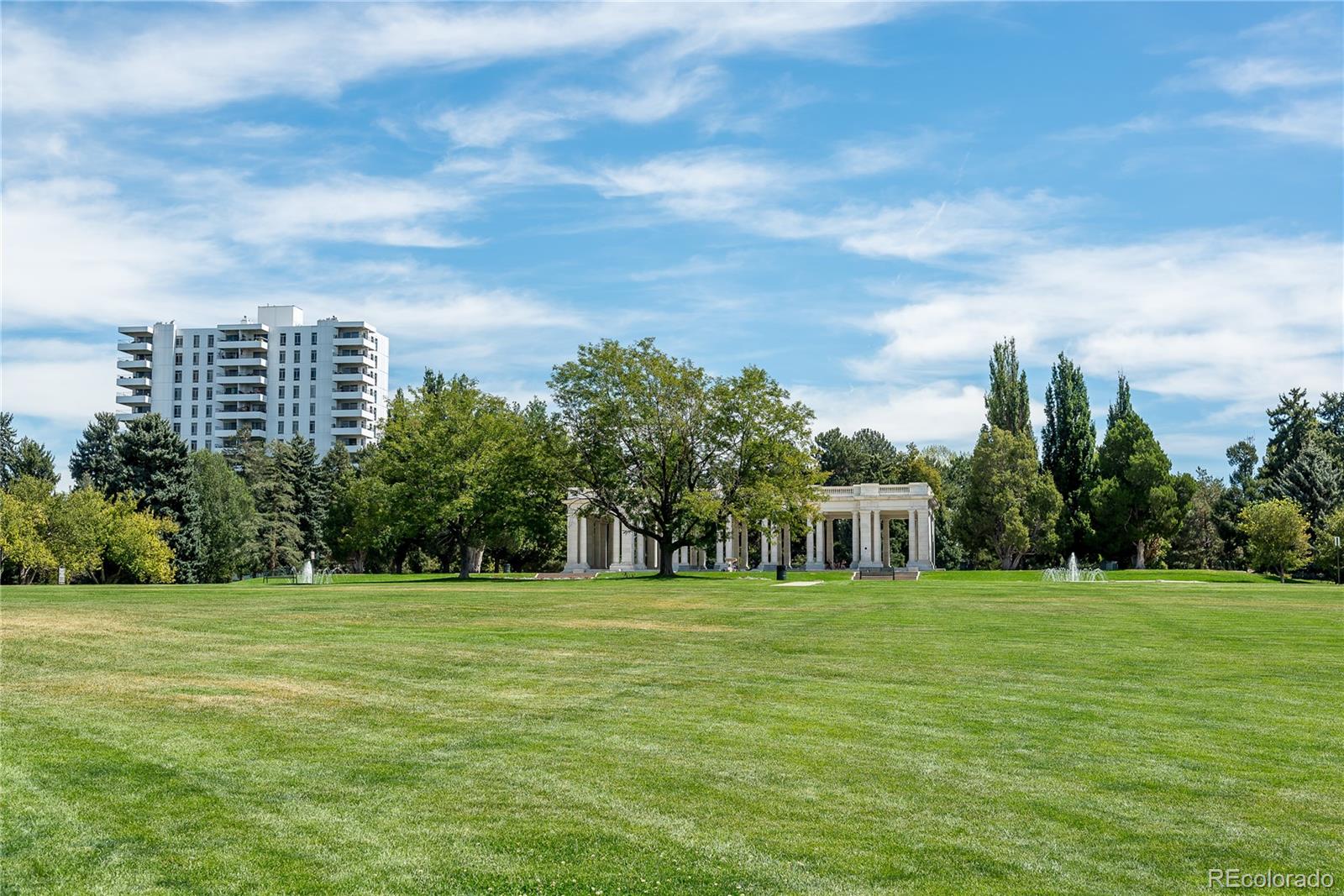 Green park with a columned pavilion and residential tower in the background.
