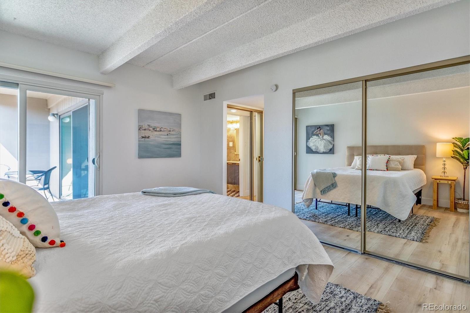 Furnished bedroom with mirrored closet doors and a sliding glass door to a balcony.