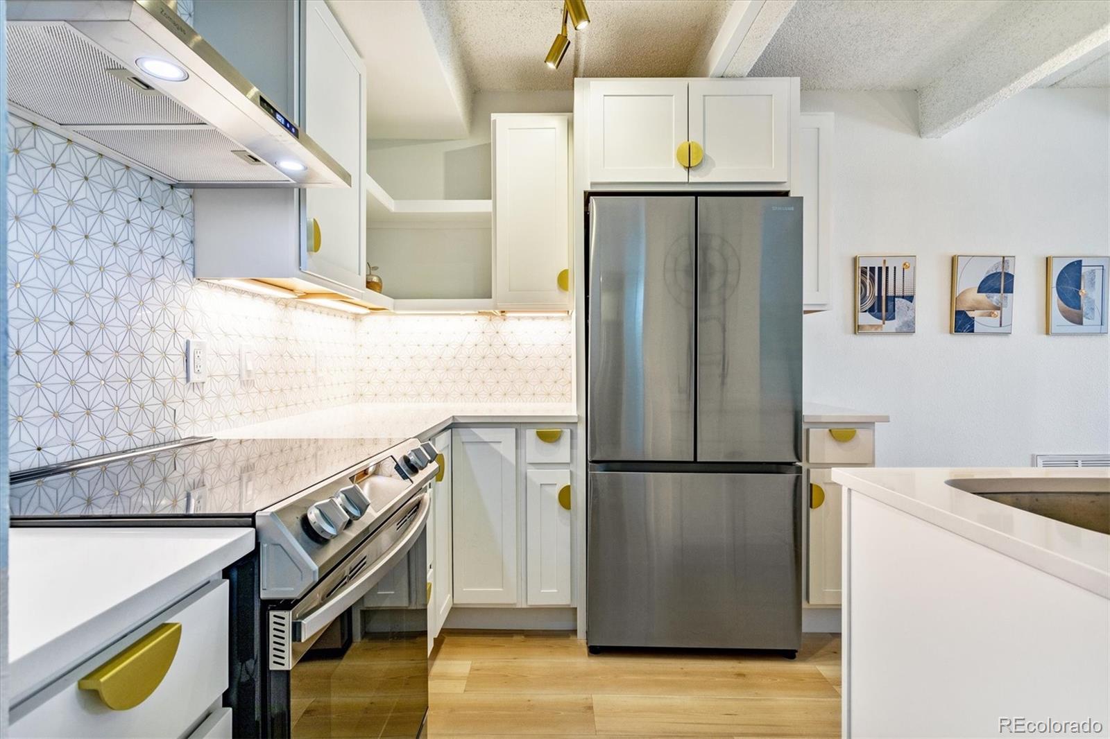 Renovated kitchen with a geometric backsplash, yellow cabinet pulls, and stainless steel appliances.
