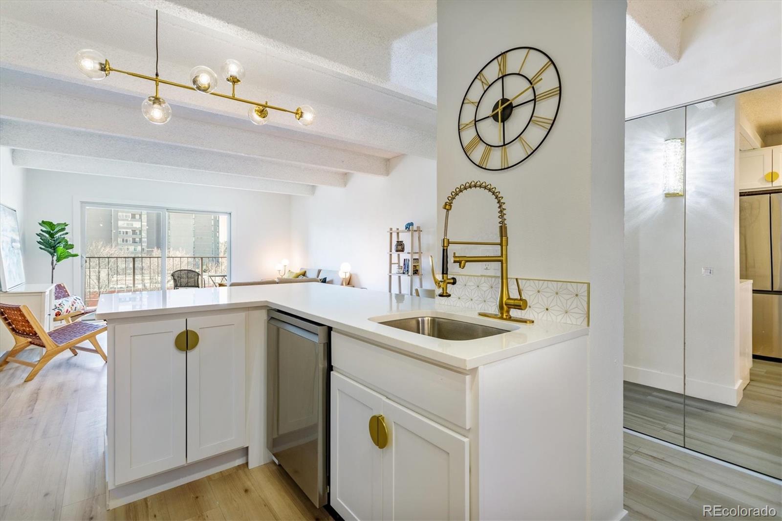Open-plan condo kitchen with a white island, gold fixtures, and a balcony beyond.