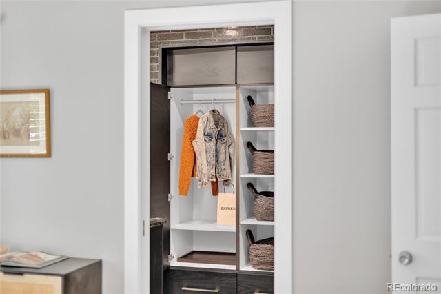 Built-in closet with hanging clothes, woven baskets, and dark drawers.