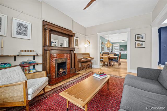 Living room with a brick fireplace, dark wood mantel, red patterned rug, and adjoining dining room.