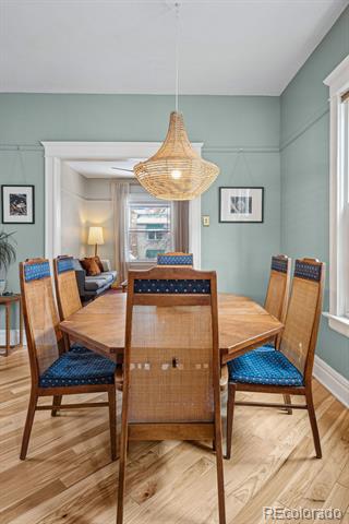 Dining room with a round wooden table, blue-cushioned chairs, and a woven pendant light.