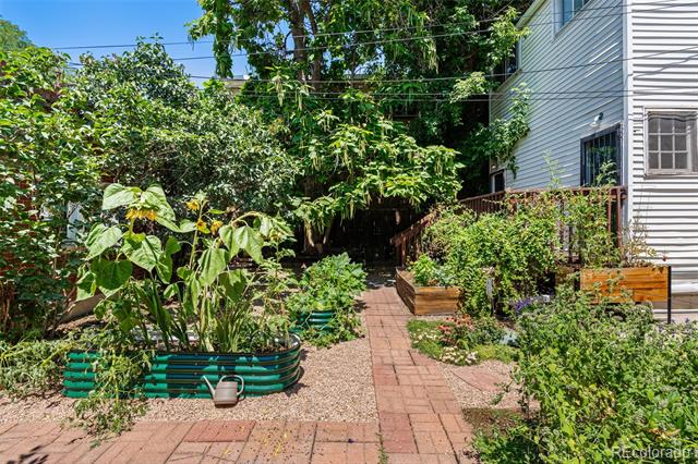 Garden beside a home with raised planting beds and a brick path.