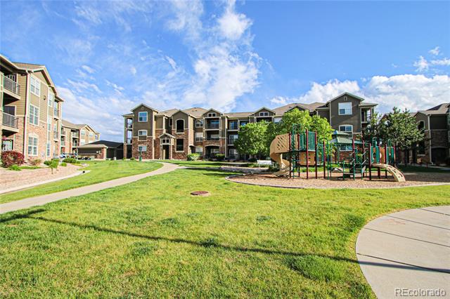 Apartment complex courtyard with a playground, grassy lawn, and curving walking paths.
