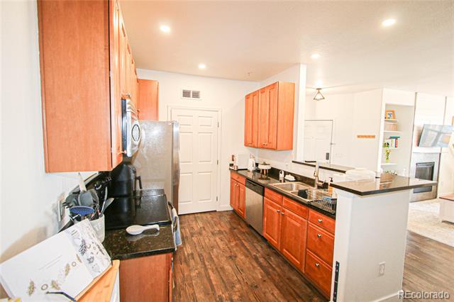 Kitchen with orange-toned cabinets, dark countertops, stainless steel appliances, and a central island.