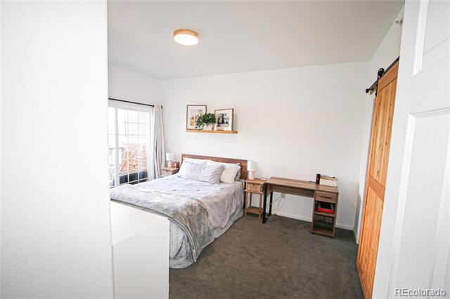 Bedroom with a bed, wall shelf, desk, and sliding glass doors.