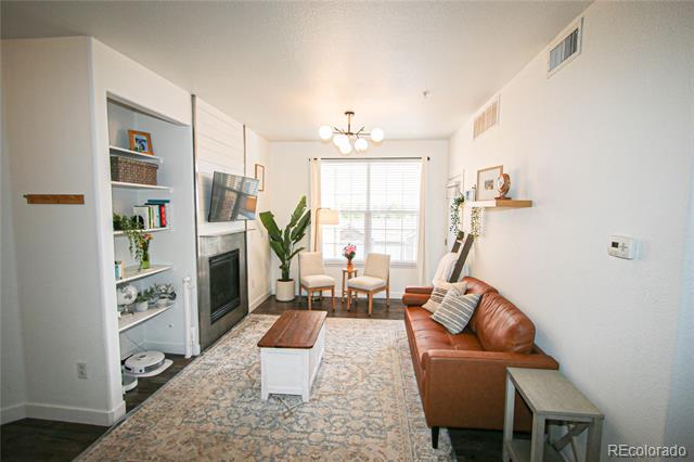 Living room with a leather sofa, built-in shelves, fireplace, and chairs by a large window.