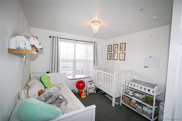 Nursery with a white crib, a pillow-filled bed, and a changing table beside a bright window.