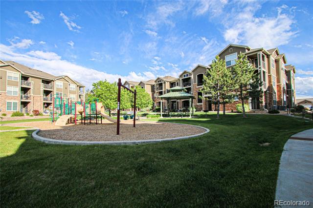 Apartment buildings surround a landscaped courtyard with a playground and broad lawn.