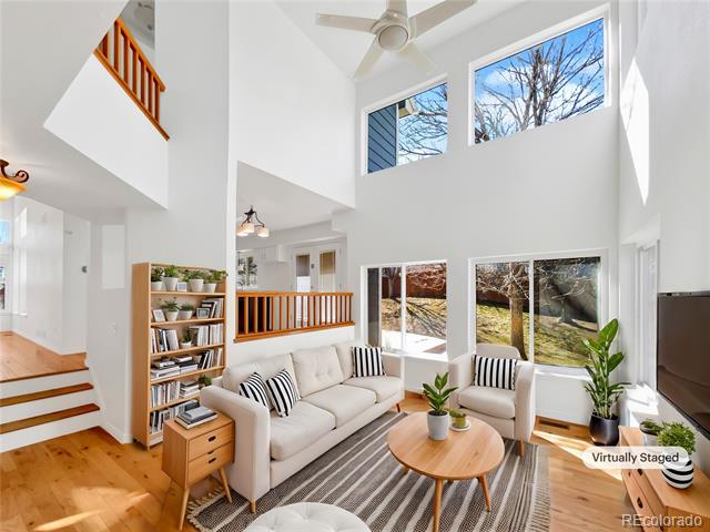 Double-height living room with a white sofa, tall windows, and hardwood floors.