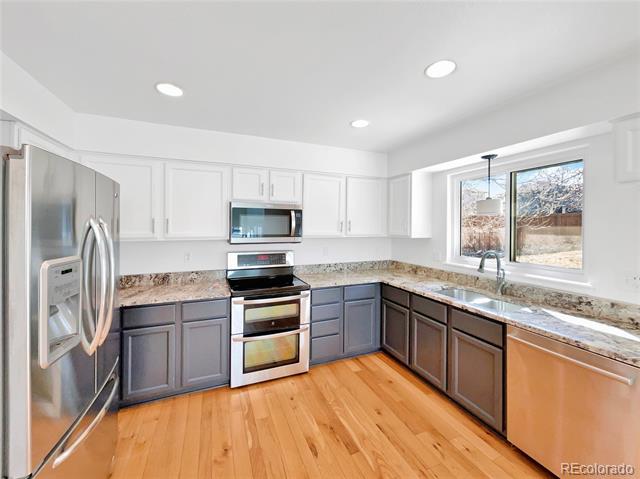 Kitchen with gray lower cabinets, granite countertops, stainless steel appliances, and hardwood floors.