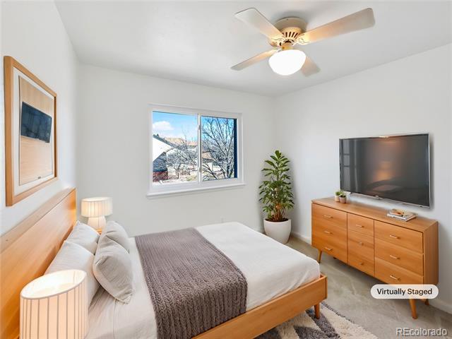 Bedroom with a wooden bed, gray throw, ceiling fan, and television on a dresser.