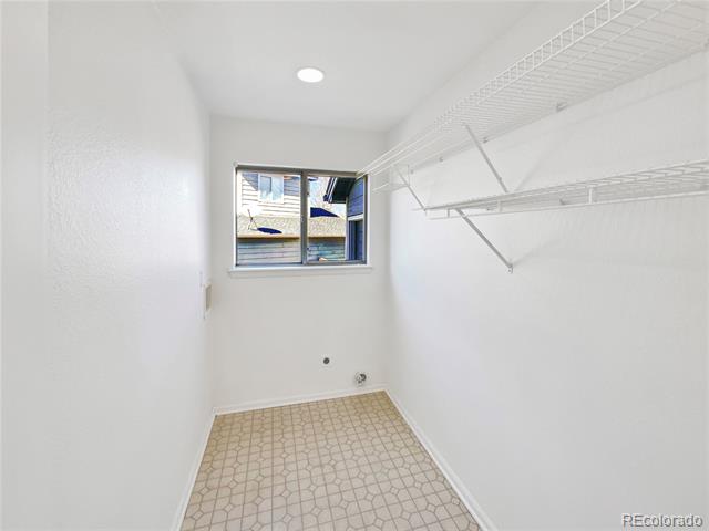 Empty laundry room with patterned tile, washer hookups, a window, and wire shelving.