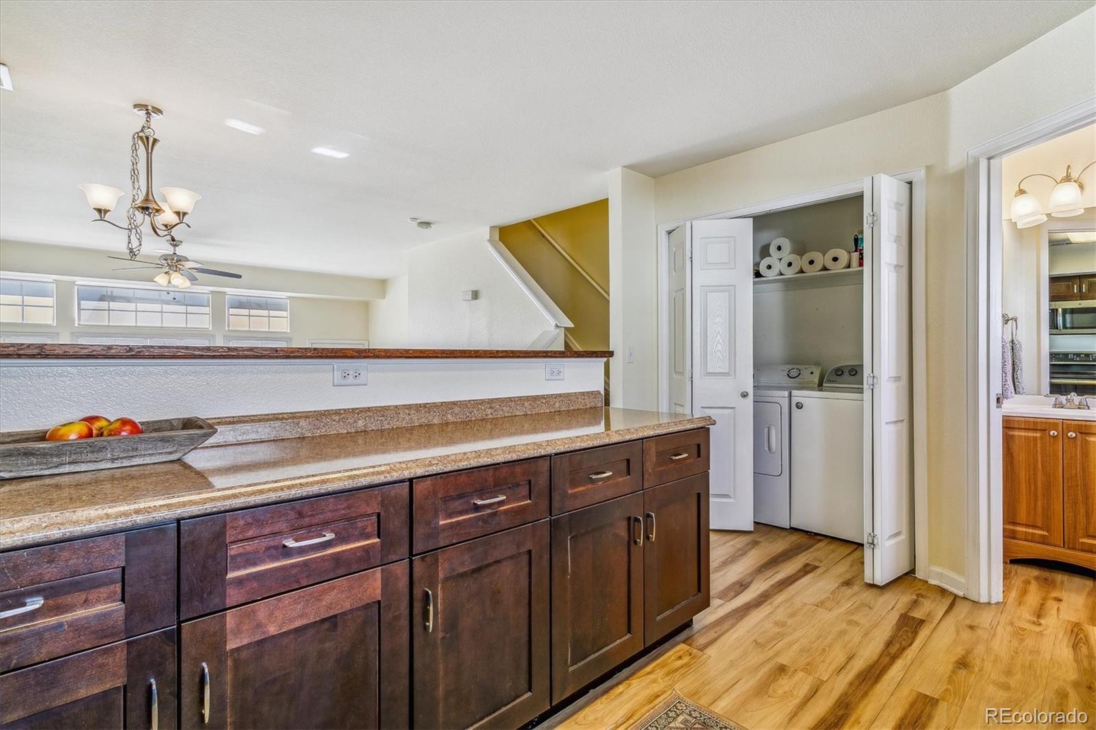 Kitchen with a raised stone counter, dark wood cabinets, and an open laundry closet.