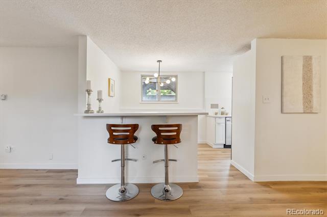 Kitchen breakfast bar with two wooden stools and light wood flooring.