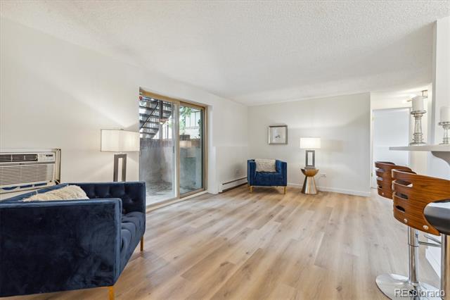 Living room with light wood floors, navy seating, and a sliding glass door to a patio.