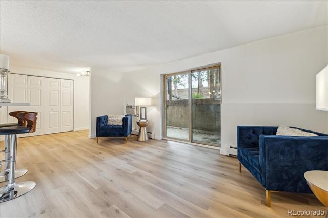 Living room with navy sofas, pale wood floors, and sliding glass doors to a fenced patio.