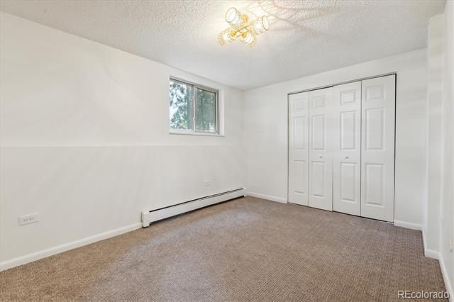 Empty bedroom with beige carpet, a wide white paneled closet, and a small window.