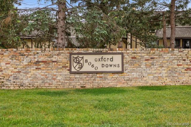 Brick entrance wall with an “Oxford 8060 Downs” sign, backed by trees.