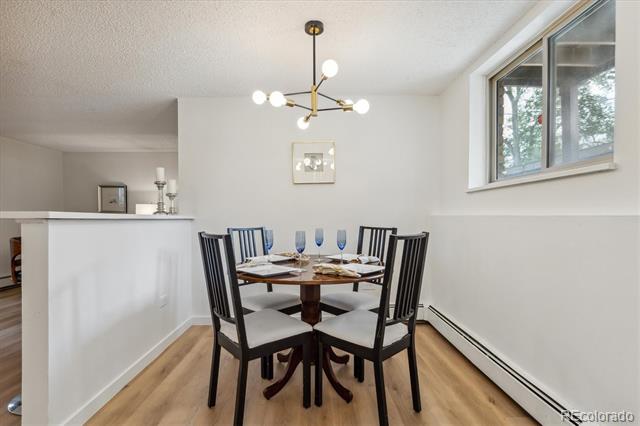 Dining area with a set table, black chairs, modern chandelier, and large window.