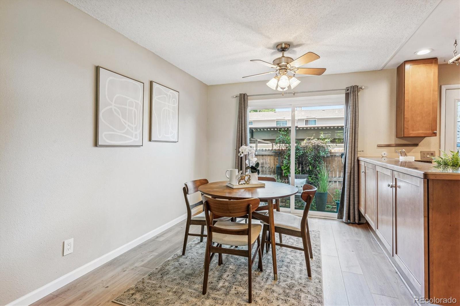 Dining area with a round wooden table beside kitchen cabinetry and sliding glass doors to a patio.