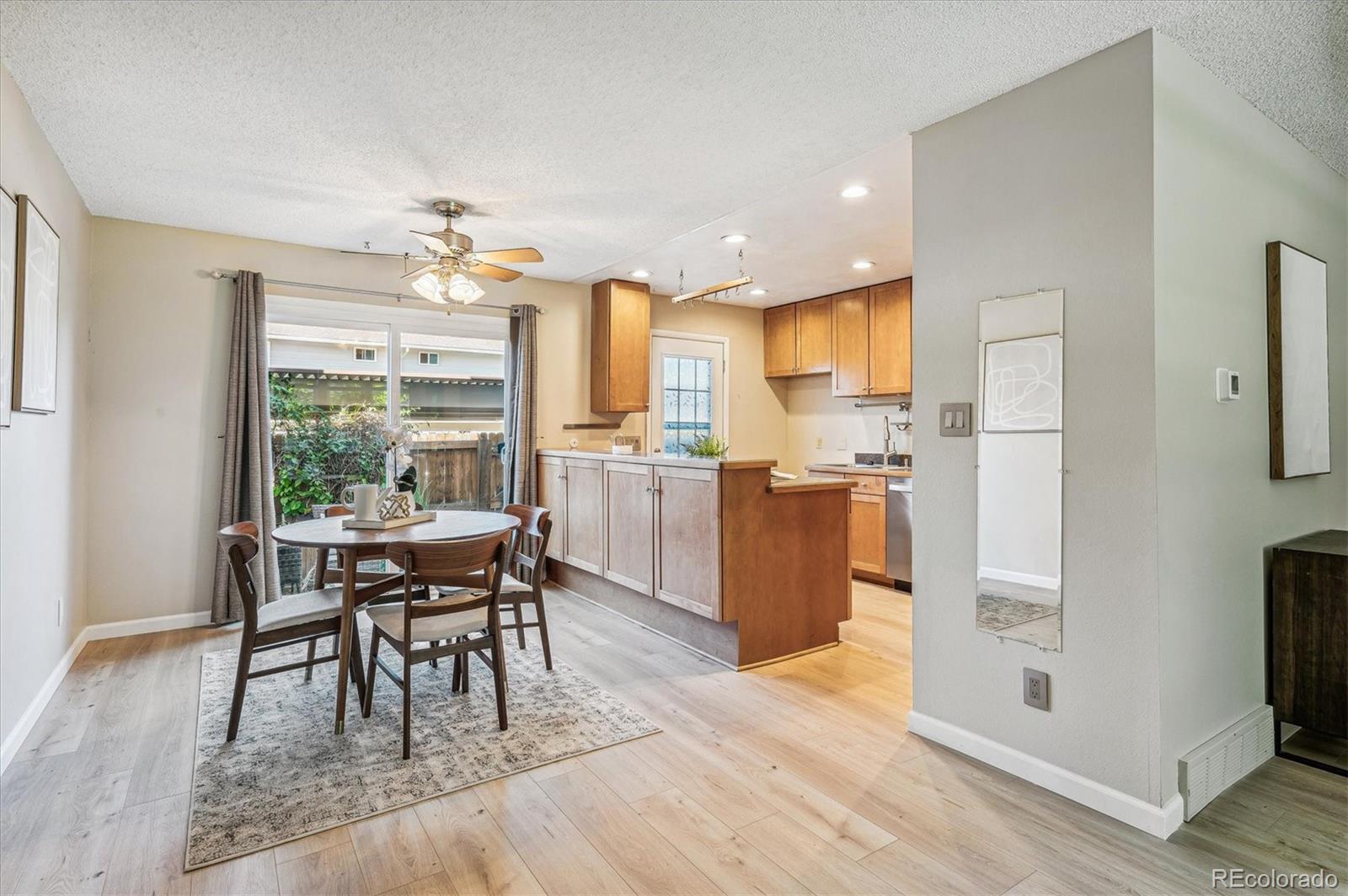 Dining area beside an open kitchen, with a round table near sliding glass doors and a wood-cabinet peninsula.