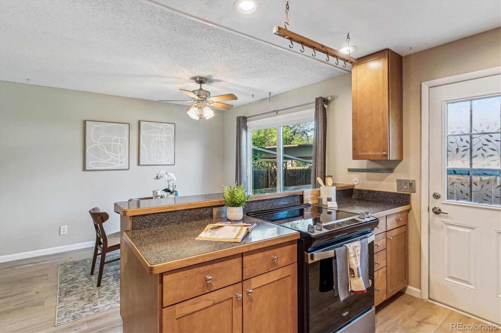 Kitchen with warm wood cabinets, speckled counters, black range, and sliding glass door to the yard.