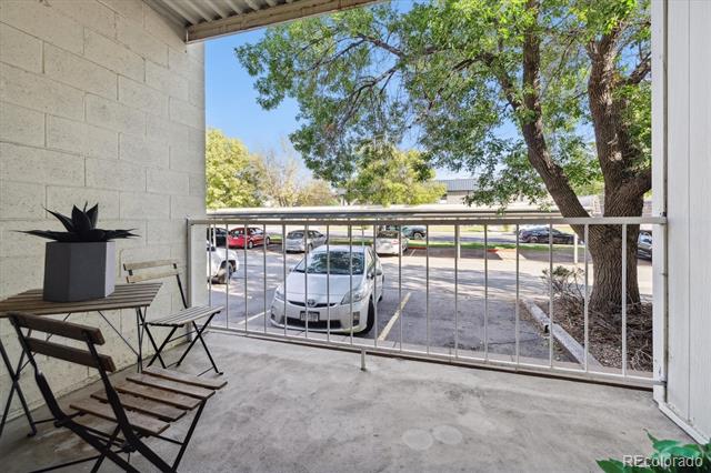 Covered patio with folding chairs overlooking a parking lot and mature trees.