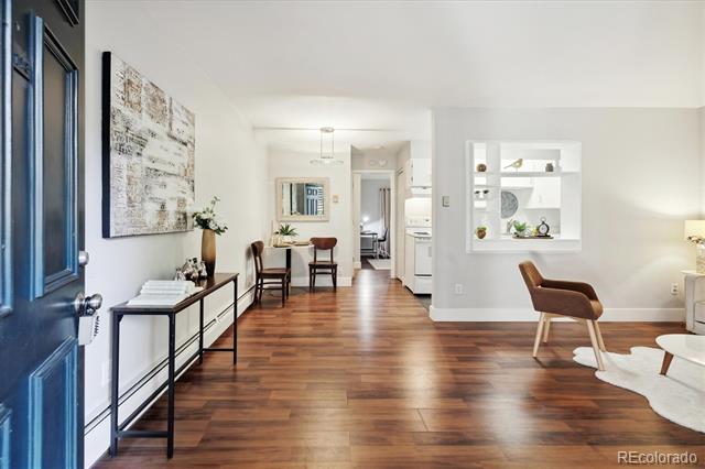 Condo interior with wood floors, a dining area, and an open kitchen.