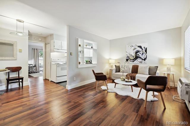 Staged living room with hardwood floors, a sofa, and an open view into the kitchen.