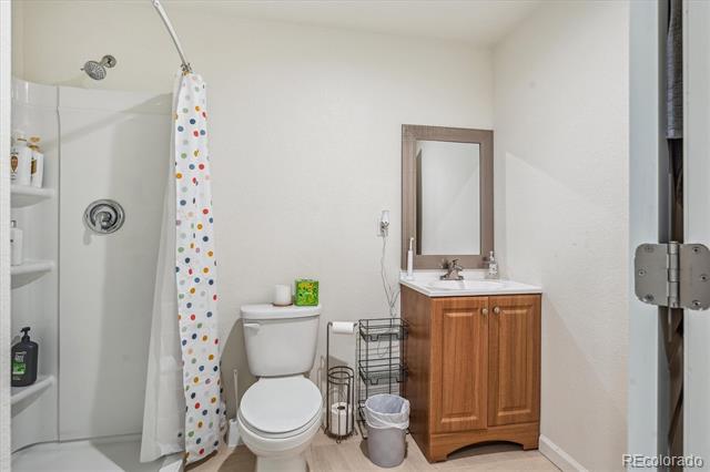Bathroom with a polka-dot shower curtain, toilet, wood vanity, and mirror.