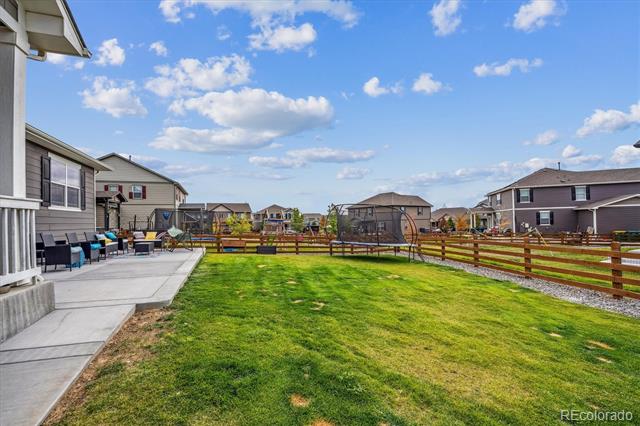 Backyard lawn and fenced yard beside a concrete patio with outdoor seating.