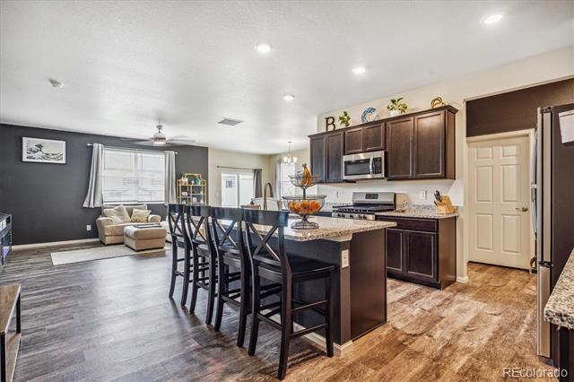 Open-plan kitchen with a granite island and breakfast bar adjoining a living area with a gray accent wall.