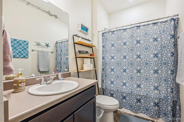 Bathroom with a dark wood vanity, white sink, and blue-and-white patterned shower curtain.